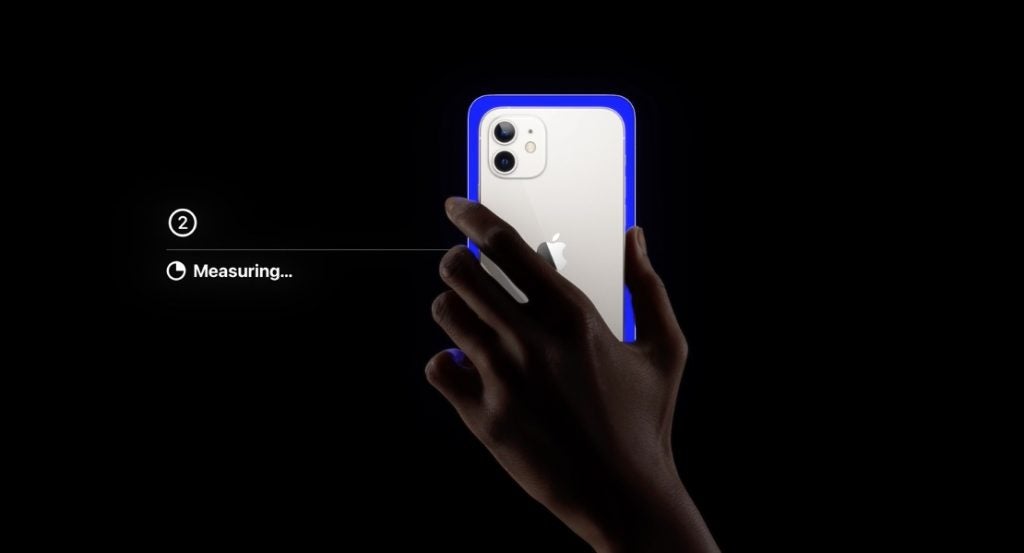 Un iPhone azul blanco sostenido en la mano sobre un fondo negro, mostrando el balance de color del Apple TV