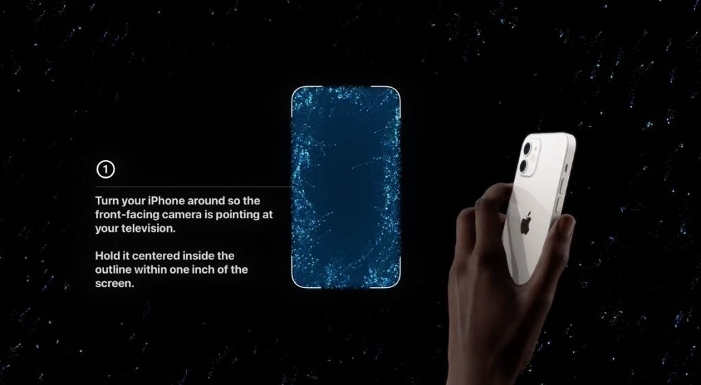 Apple TV muestra la función de ajuste de balance de color sobre un fondo negro con un iPhone en la mano a la derecha Un iPhone blanco en la mano sobre una pantalla de fondo negro, mostrando la forma de un iPhone en azul y la dirección para colocarlo