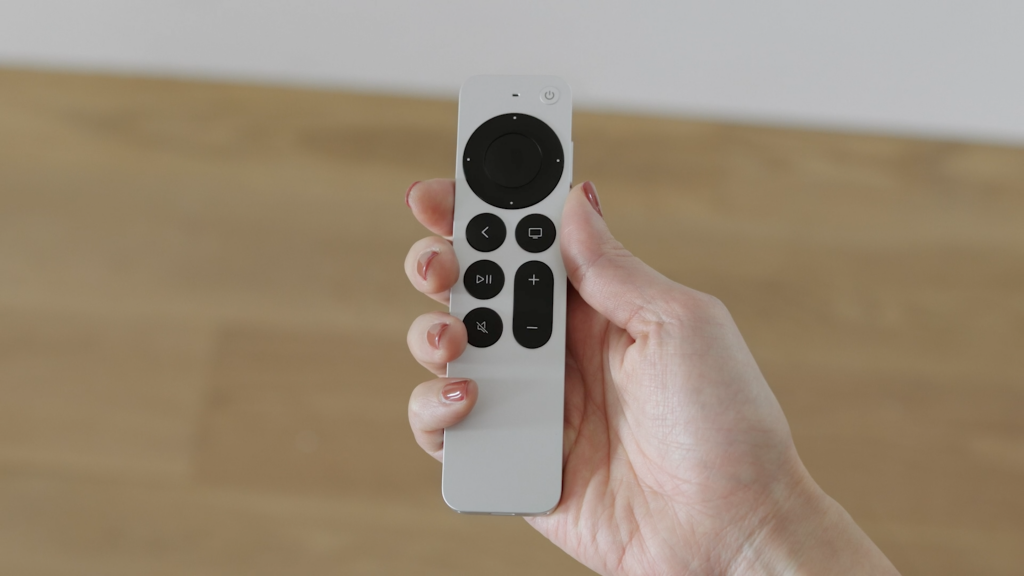 El nuevo Apple Siri Remote, Apple TV Box negro y su control remoto blanco con teclas negras, todo sobre un fondo blanco.