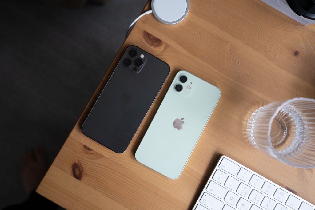 Un iPhone 12 Pro en blanco y negro boca abajo sobre una mesa de madera, vista desde arriba