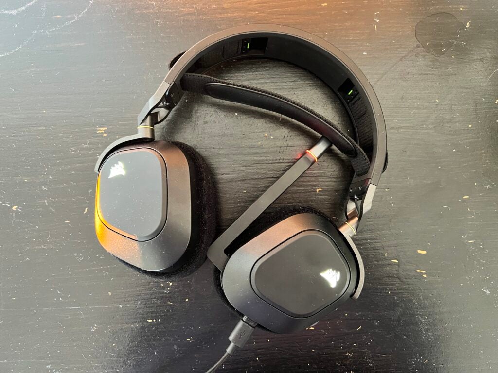 Los auriculares Corsair HS80 RGB yacen sobre un escritorio negro