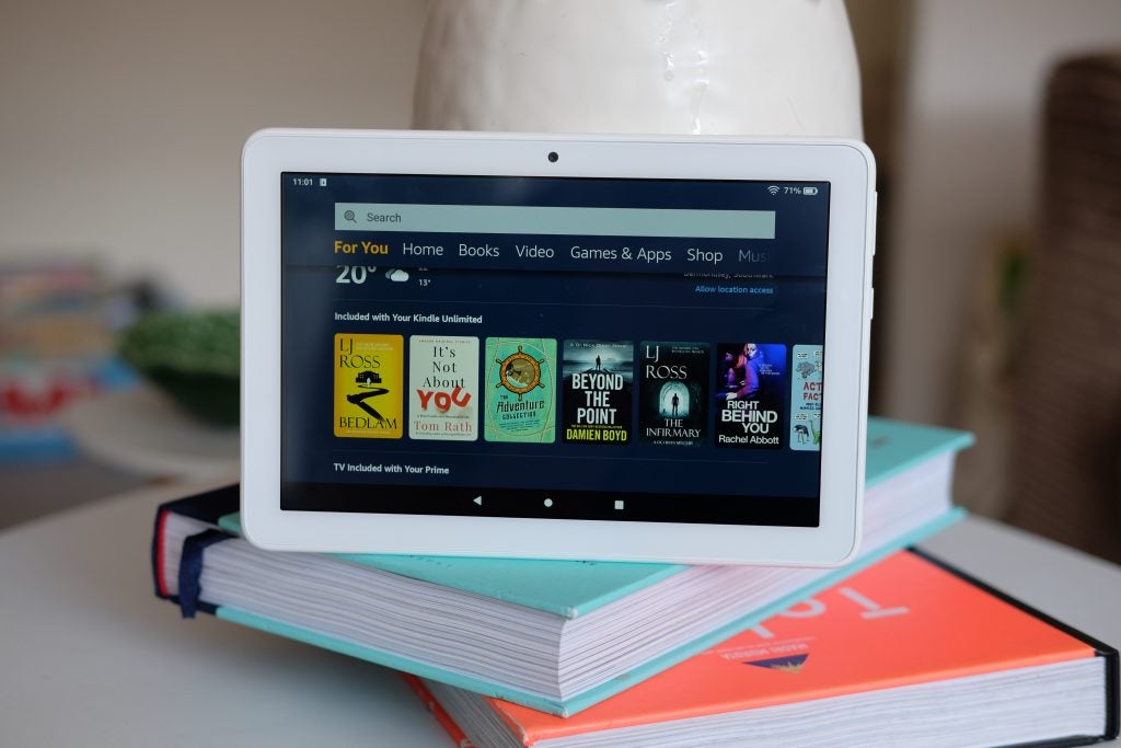 Un Kindle de Amazon blanco parado sobre libros que muestra la pantalla de inicio de la tienda