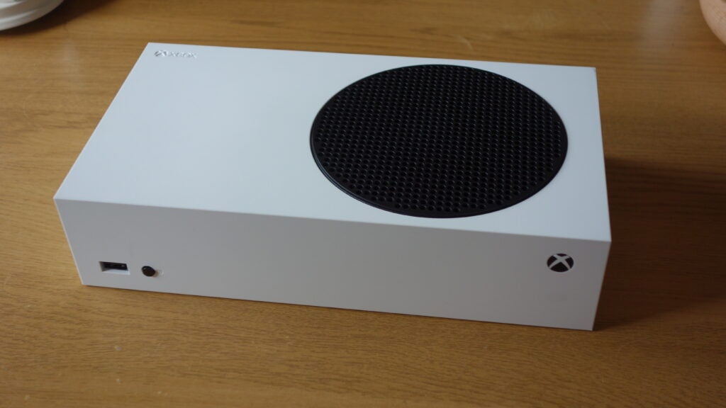 Vista lateral derecha de una Xbox blanca sobre una mesa de madera