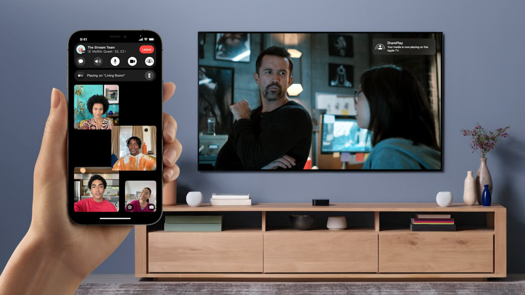 Un televisor que reproduce un video y un iPhone sostenido en el frente que muestra el uso de Facetime