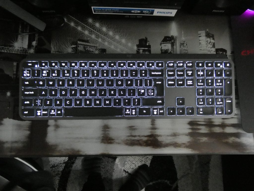 Vista desde la parte superior de un teclado Logitech MX negro sobre una mesa con luces debajo de las teclas