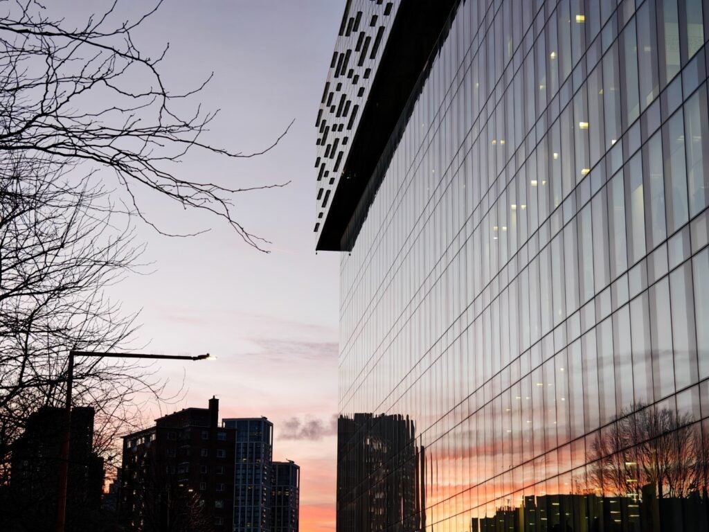 Reflexión urbana del atardecer en la fachada de cristal del edificio moderno.