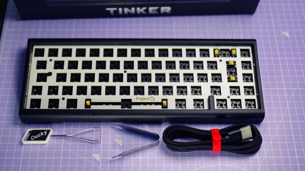 Teclado Ducky ProjectD Tinker 65 Barebones sobre escritorio con accesorios.