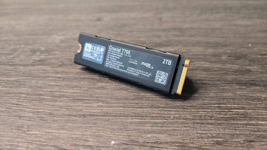 SSD PCIe T700 M.2 de Crucial con su placa posterior en exhibiciónSSD Crucial T700 2TB M.2 sobre una superficie de madera.